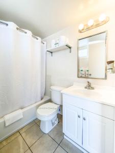 uma casa de banho com um WC, um lavatório e um espelho. em Ocean Court Beachfront Hotel em Daytona Beach
