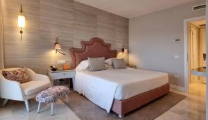 una camera con un grande letto e una sedia di CPH | Pevero Hotel a Porto Cervo