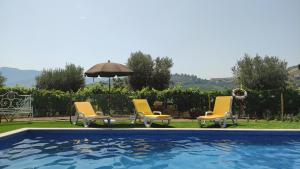 a swimming pool with three chairs and an umbrella at Quinta dos Padrinhos - Suites in the Heart of the Douro in Lamego