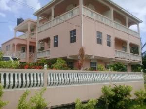 a large pink house with a white fence at Sunset Bliss Villa in Anse La Raye