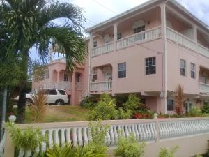 Uma casa cor-de-rosa com uma cerca branca à frente. em Best View Apartments em Anse La Raye