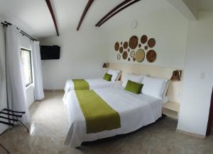Habitación blanca con 2 camas y TV de pantalla plana. en Aromarte Finca Hotel en Filandia