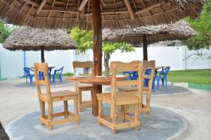 uma mesa de madeira e cadeiras debaixo de um guarda-sol de palha em Bagamoyo Spice Villa em Nungwi