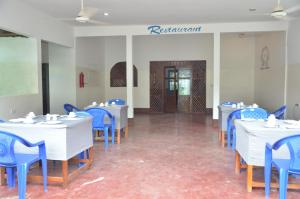 um restaurante com mesas brancas e cadeiras azuis em Bagamoyo Spice Villa em Nungwi