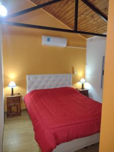 a bedroom with a red bed with two night stands at Cabañas La Comarca in Concepción del Uruguay