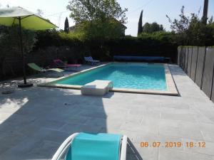 einen Pool mit 2 Stühlen und einem Sonnenschirm in der Unterkunft La maison bleue in LʼIsle-sur-la-Sorgue