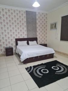 a bedroom with a large bed and a black rug at نارين للشقق المفروشة in Taif