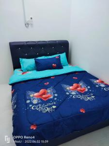 Una cama con un edredón azul con flores rojas. en Raihan Homestay Seri Iskandar Perak Near UTP UITM en Seri Iskandar