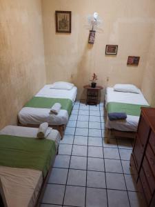 een kamer met drie bedden en een tafel erin bij Hostal Guadalajara in Guadalajara
