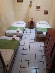 Habitación con 3 camas y suelo de baldosa. en Hostal Guadalajara, en Guadalajara