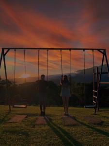 two people standing in a swing set at sunset at Cabañas El Parador in Boquete