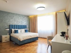 Schlafzimmer mit einem Bett mit blauem Kopfteil und einem Fenster in der Unterkunft Boutique Central in Sibiu