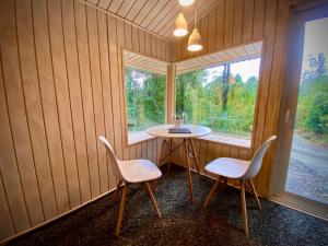 a small table and two chairs in a room with a window at Stillner Waldhaus in Puerto Varas