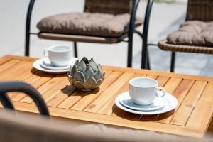 twee kopjes en schotels op een houten tafel bij Sobe in apartmaji Bama in Litija