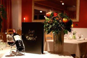 una botella de vino y un jarrón de flores sobre una mesa en Hotel Brienz, en Brienz