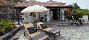 a patio with chairs and an umbrella and a table at Bungalows Aldani in Tijarafe