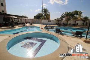 a group of three swimming pools in a resort at Apartamento confortável em caldas novas com espaço aquático, 6 piscinas , 3 hidromassagem , Bar e Restaurante , Sauna , espaço kids in Caldas Novas