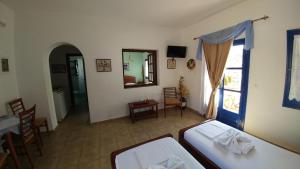 a room with two beds and a table and a mirror at Aegean Star Hotel in Karavostasi