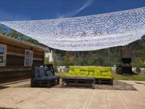 eine Terrasse mit 2 Sofas, einem Tisch und einem Netz in der Unterkunft La Cabaña del Alberche in Navaluenga