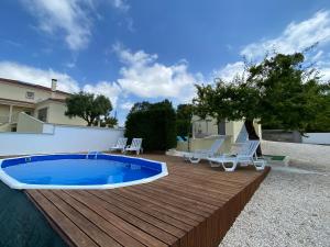 una terraza de madera con piscina y sillas. en Casa Ameixa, en Alcobaça