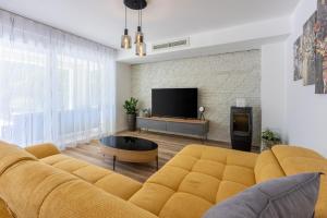 a living room with a yellow couch and a tv at Villa Una in Krk