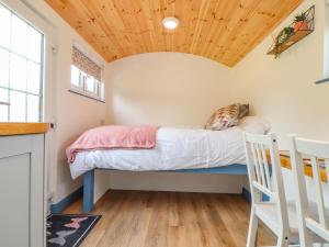 a bed in a tiny house with a wooden ceiling at Rose in Redruth