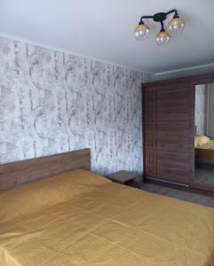 a bedroom with a bed and a stone wall at Kandavas Street City Center Apartment in Daugavpils