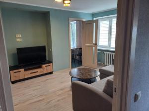 a living room with a tv and a couch and a table at Kandavas Street City Center Apartment in Daugavpils