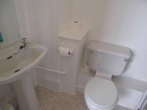 a white bathroom with a toilet and a sink at The Sandhill in Sandown