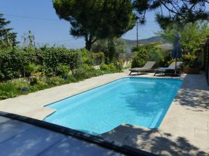 una piscina en un patio con 2 tumbonas en Maisonnette proche des calanques , les Bruyères, en Marsella