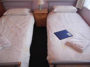 two twin beds in a room with a book on it at The Sandhill in Sandown