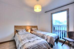 a bedroom with two beds and a window and a chair at Appartement 60M2 - TELECABINE SAINT GERVAIS - 201 in Saint-Gervais-les-Bains