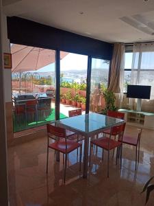 a dining room with a glass table and chairs at Appartement bord de mer et piscine en option in Tangier