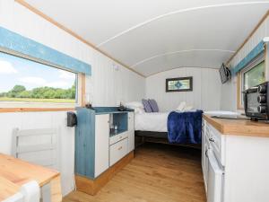 Habitación pequeña con cama y ventana en Shepherds Hut, en Lostwithiel