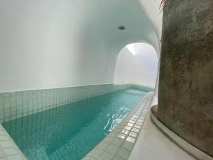 uma piscina de água com um arco num edifício em Villa Orpheus Santorini em Megalochori
