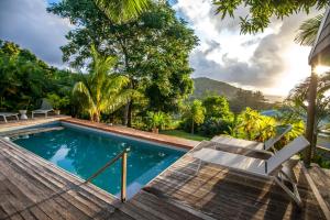 una piscina con terraza y silla en Red Coconut Self-Catering en Mahe