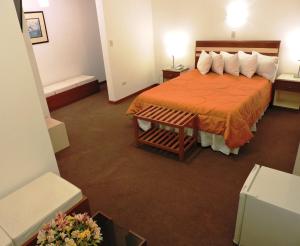 um quarto de hotel com uma cama com uma colcha laranja em Hotel San Andres em Arequipa