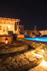 a resort with a pool and lounge chairs at night at Diamond Of Mykonos in Ano Mera