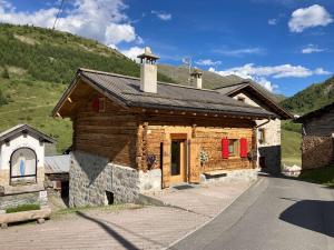 un pequeño edificio de madera con puertas rojas y una iglesia en Baita Rini, en Livigno