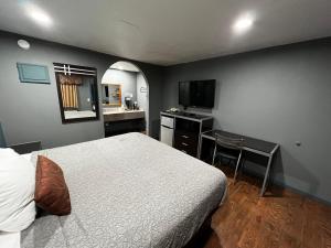 a bedroom with a bed and a desk and a kitchen at Relax Inn Ashdown in Ashdown