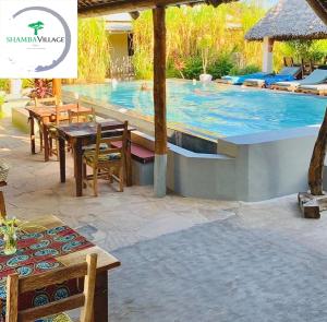 a swimming pool with a table and chairs next to it at Shamba Village in Paje
