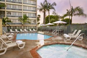 a beach with a pool, chairs, and a pool table at ALO Hotel by Ayres in Anaheim