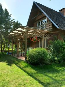 a house with a wooden pergola in the yard at A summer house Zarabie Domek letniskowy Zarabie in Myślenice