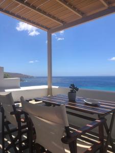 een tafel en stoelen op een balkon met uitzicht op de oceaan bij Meltemi Tinos in Agios Romanos