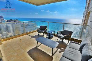 a balcony with a couch and chairs and the ocean at Sea view family relax apartment in Netanya