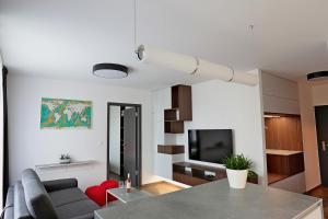 uma sala de estar com uma mesa, um sofá e uma televisão em Modern apartment near the city centre URBAN em Bratislava