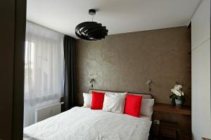 1 dormitorio con 1 cama con almohadas rojas y blancas en Modern apartment near the city centre URBAN, en Bratislava
