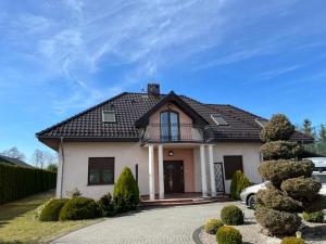 a white house with a black roof and a driveway at LakeHouse in Giewartów