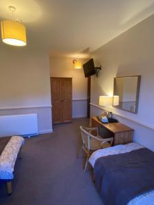 a room with two beds and a desk and a television at Queens Ground in Sheffield