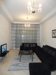 sala de estar con sofá negro y lámpara de araña en Appartement LaVie, en Túnez